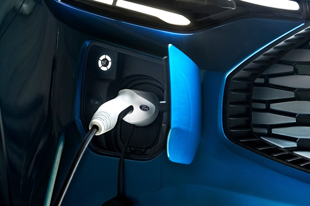 Ford E-Transit Custom in Blau. Detailansicht des Ladeanschluss mit angestecktem Ladekabel.