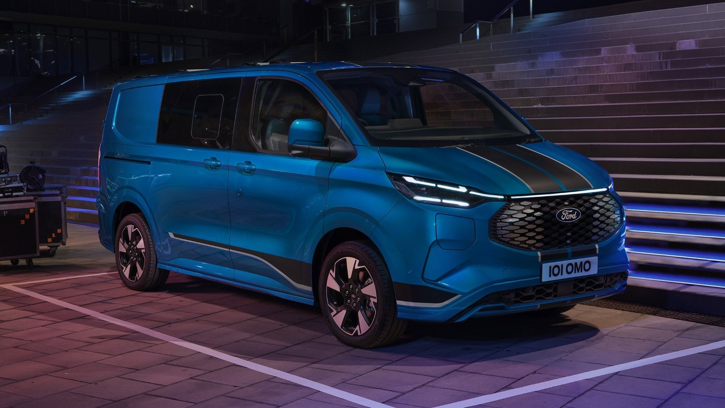 Ford Transit Custom Sport in Blau. Dreiviertelansicht, stehend auf einem Parkplatz bei Nacht.