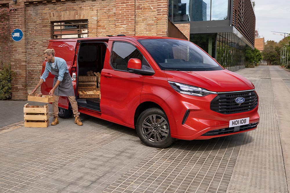 Ford Transit Custom in Rot. Mann beladet den Transporter, Ansicht der elektrischen Schiebetür.