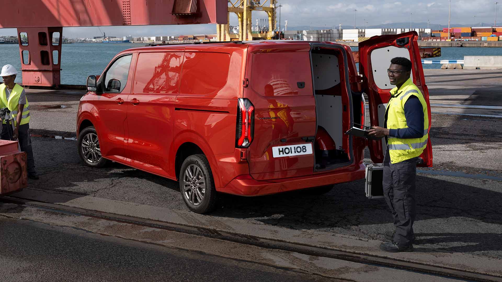 Ford Transit Custom in Rot. Person öffnet die Hecktür des Fahrzeugs.