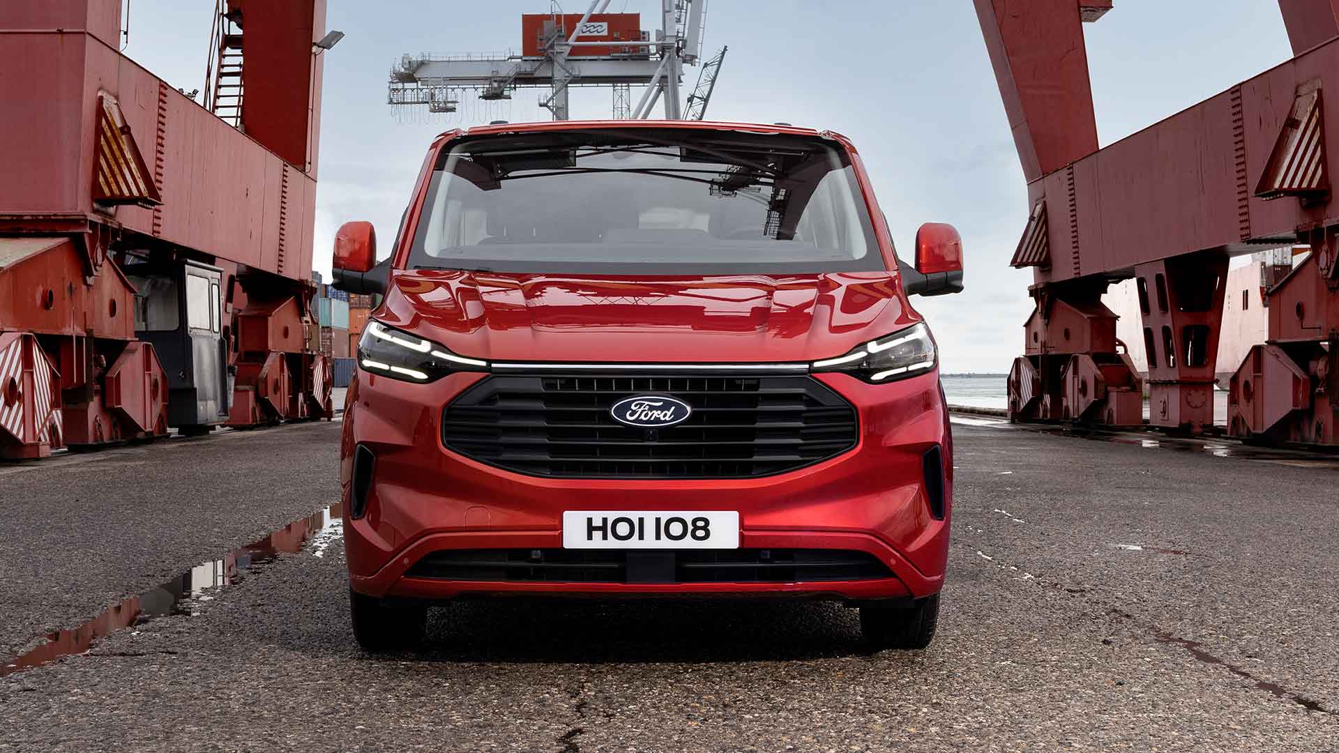 Transit Custom in Rot. Frontansicht, parkt auf einem Industriehafen.