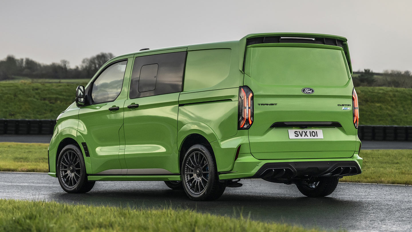 Ford Transit Custom MS-RT in Grün. Heckansicht, parkt auf einer Rennstrecke mit anliegender Grünfläche.