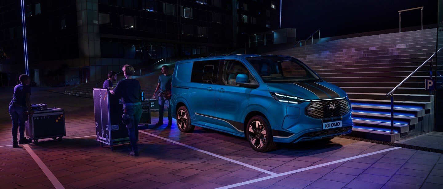 Ford Transit Custom in Blau. Dreiviertelansicht, parkt vor Treppen.