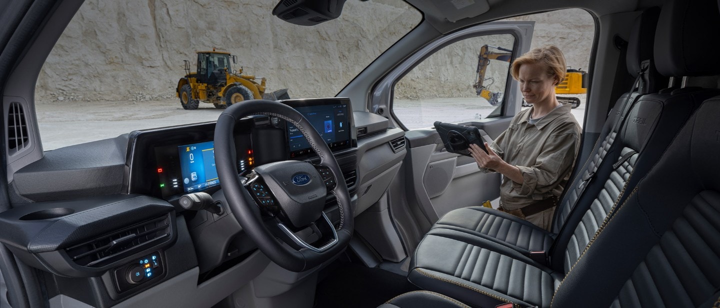 Ford Transit Custom Innenraum. Blick in Fahrerkabine und Frau hält ein Tablet.
