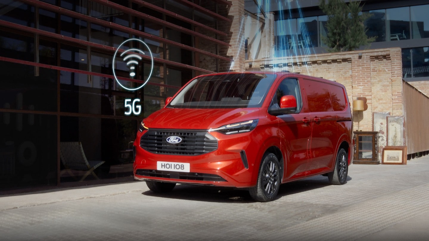 Ford Transit Custom in Rot. Dreiviertelansicht, parkt vor einem Wohnhaus mit 5G-Grafik.