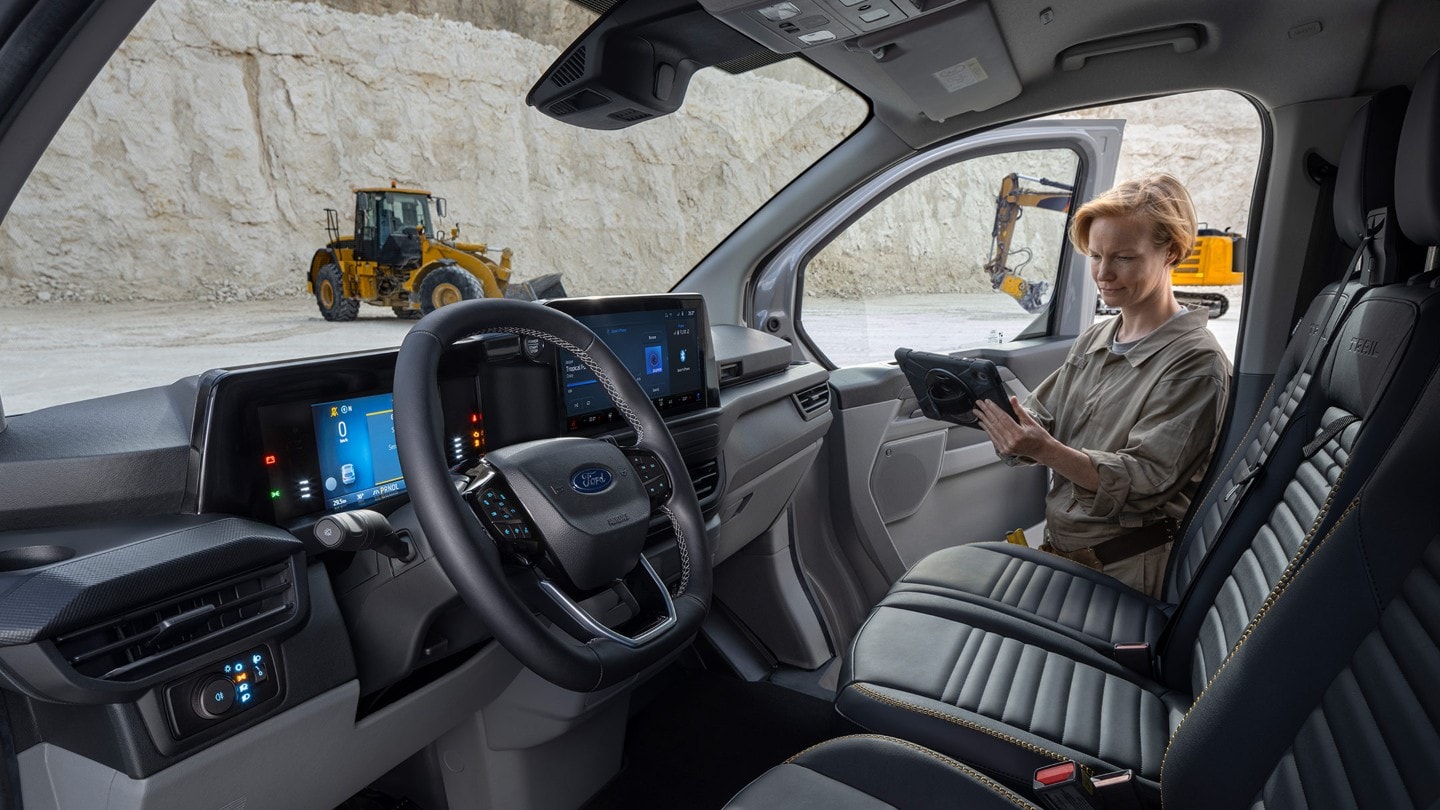 Ford Transit Custom Innenraum. Blick in Fahrerkabine und Frau hält ein Tablet.
