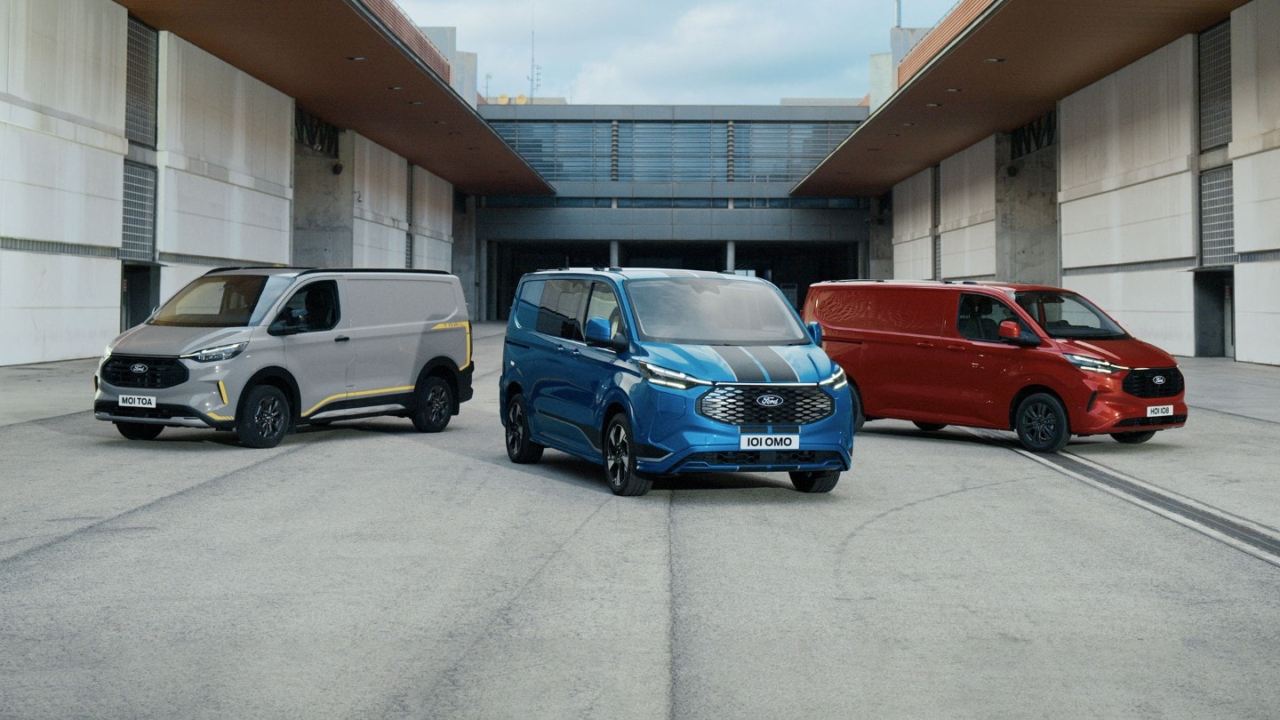 Ford Transit Custom in Grau, Blau und Rot parken vor einem Gebäude