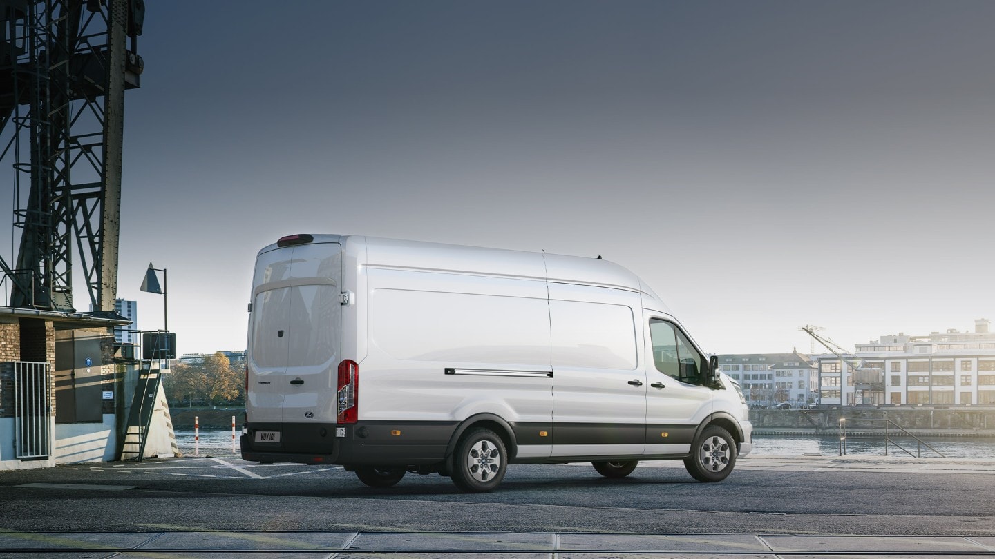 Ford Transit in Weiß. Dreiviertelansicht, stehend an einem Hafen bei Sonnenuntergang.