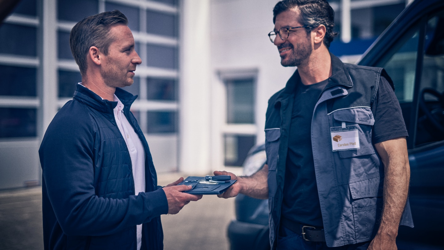 Ford Mitarbeiter und Kunde tauschen miteinander Schlüssel.