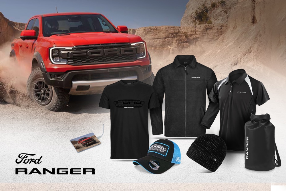 Ford Ranger Kollektion mit schwarzem T-Shirt, Jacke, Polo, Kappe, Beanie und Wetpack, und einem roten Ranger im Hintergrund.