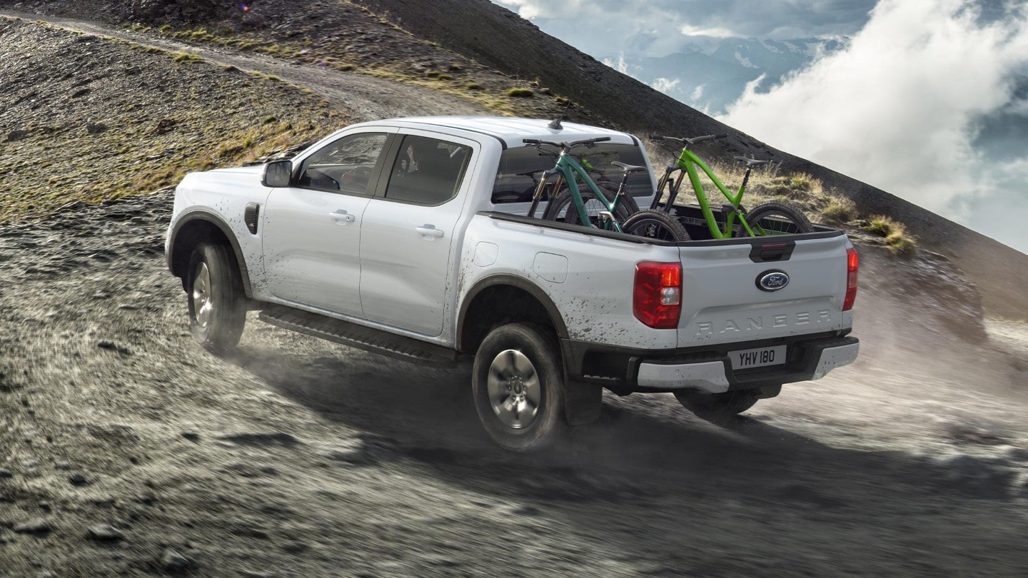 Ford Ranger Plug-in-Hybrid in Weiß. Dreiviertelansicht, fahrend auf einer unbefestigten Straße.