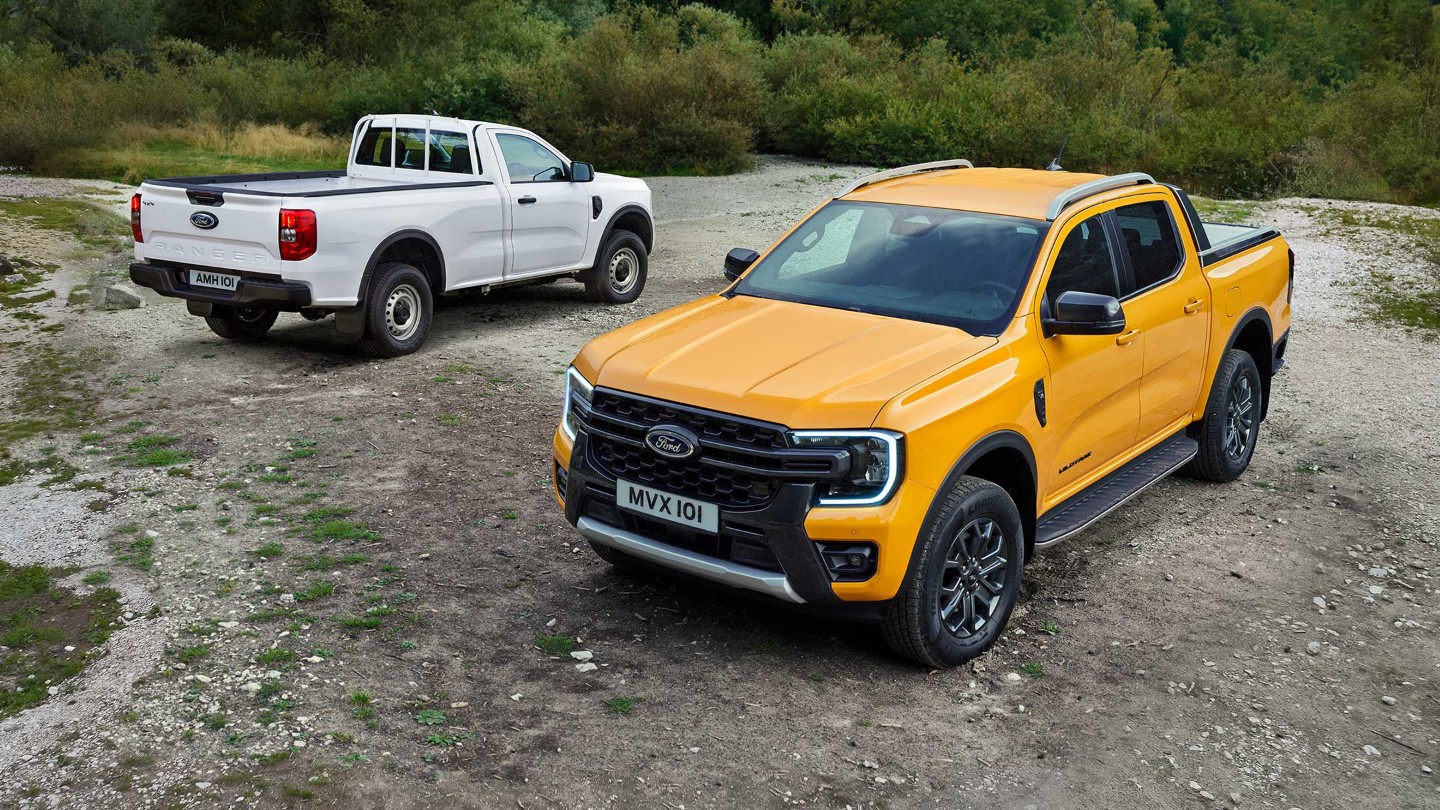 Ford Ranger in Orange, Dreiviertelansicht. Ford Ranger in Weiß, Heckansicht. Parkend auf einer unebenen Fläche.