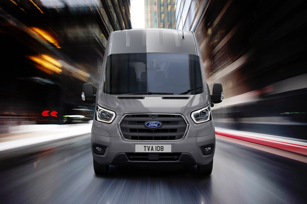 Ford Transit in Grau. Frontansicht während der Fahrt durch die Stadt.