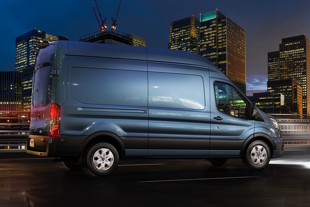 Ford Transit Kastenwagen in Blau. Seitenansicht, bei Nacht während der Fahrt durch die Stadt.