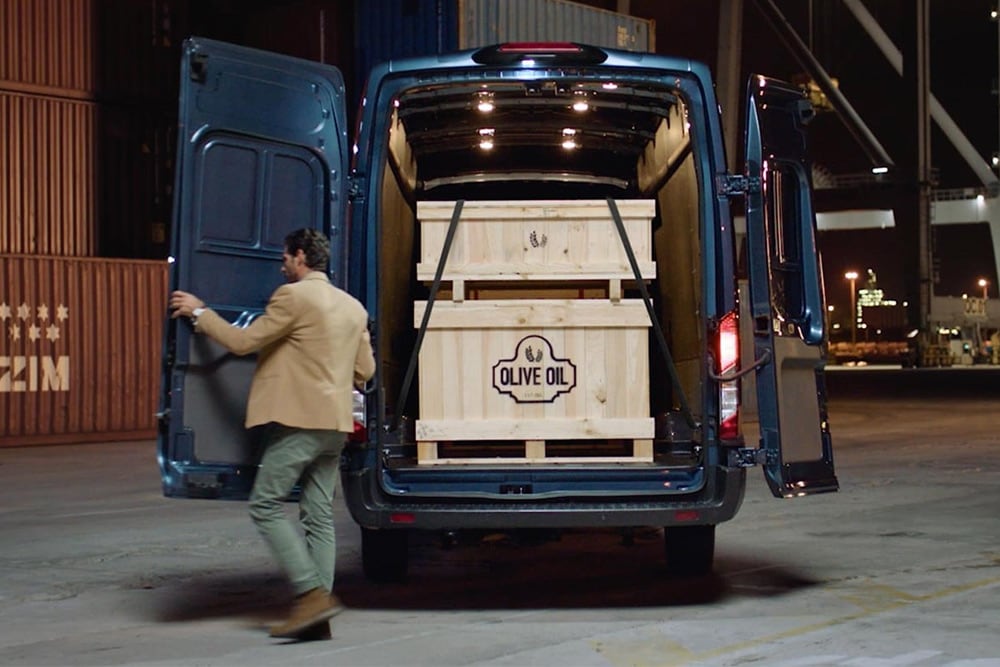 Ford Transit Kastenwagen in Blau mit geöffneter Hecktüre und Ladegut im Innenraum.