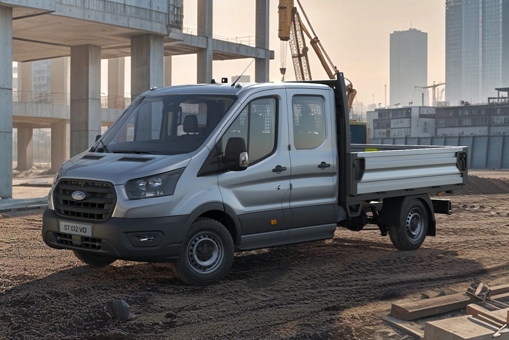 Ford Transit Fahrgestell mit Doppelkabine in Silber, auf einer Baustelle.