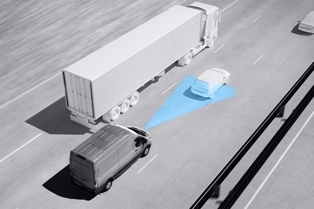 Ford Transit auf der Autobahn mit blau hervorgehobenem Bereich zur Darstellung des adaptiven Tempomaten. 