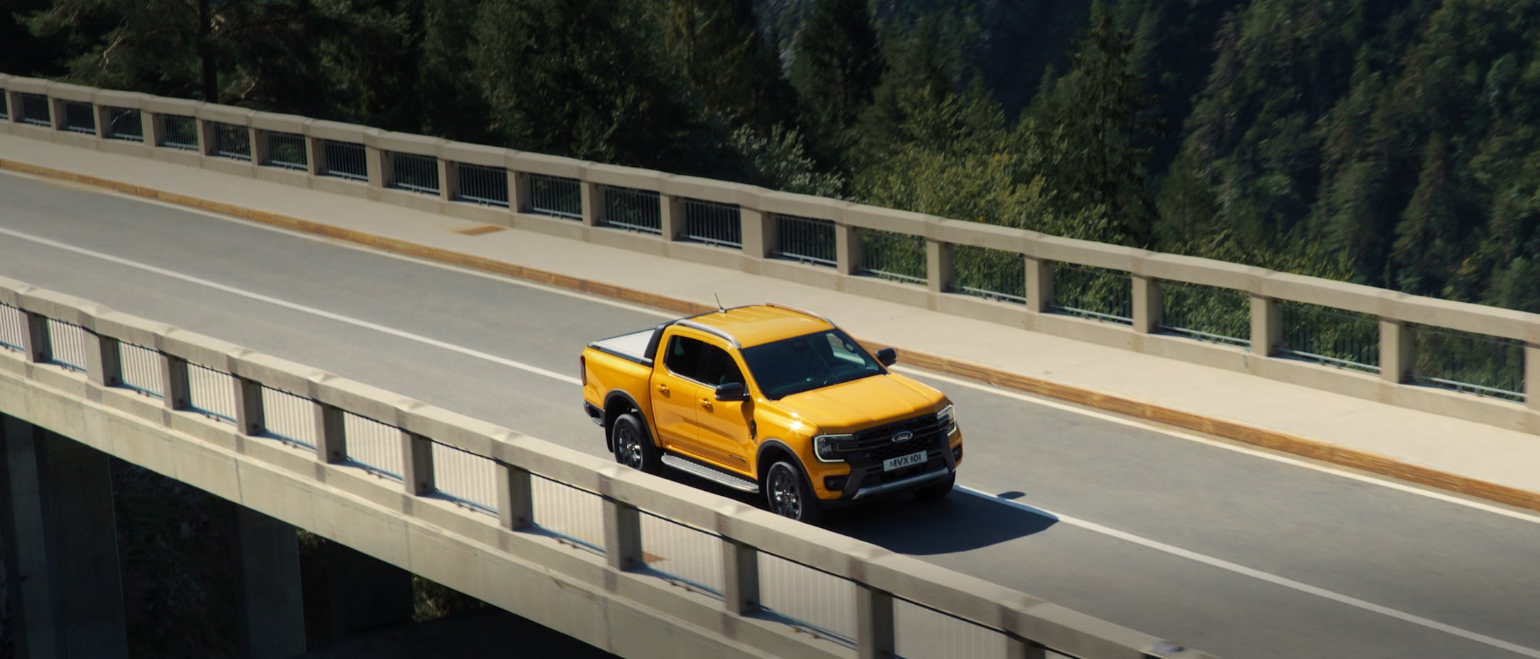 Ford Ranger in Orange. Dreiviertelansicht, fährt auf einer Brücke