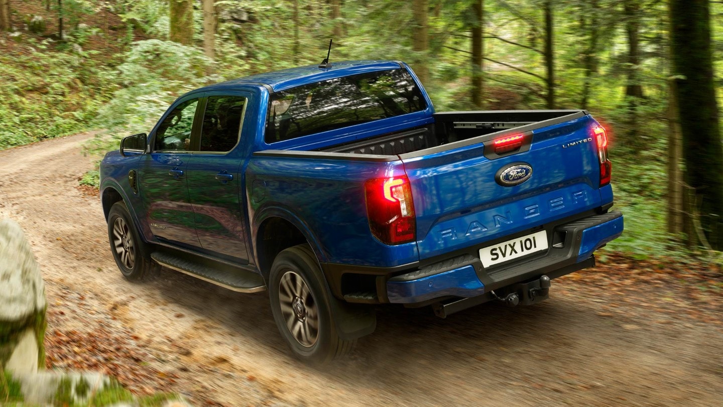 Ford Ranger in Blau. Heckansicht, fährt auf Waldweg