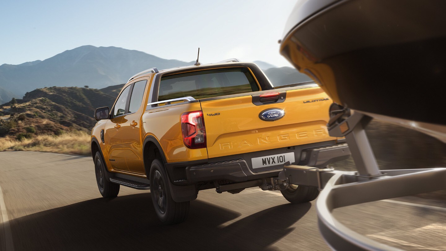 Ford Ranger in Orange. Heckansicht, zieht Anhänger mit Boot