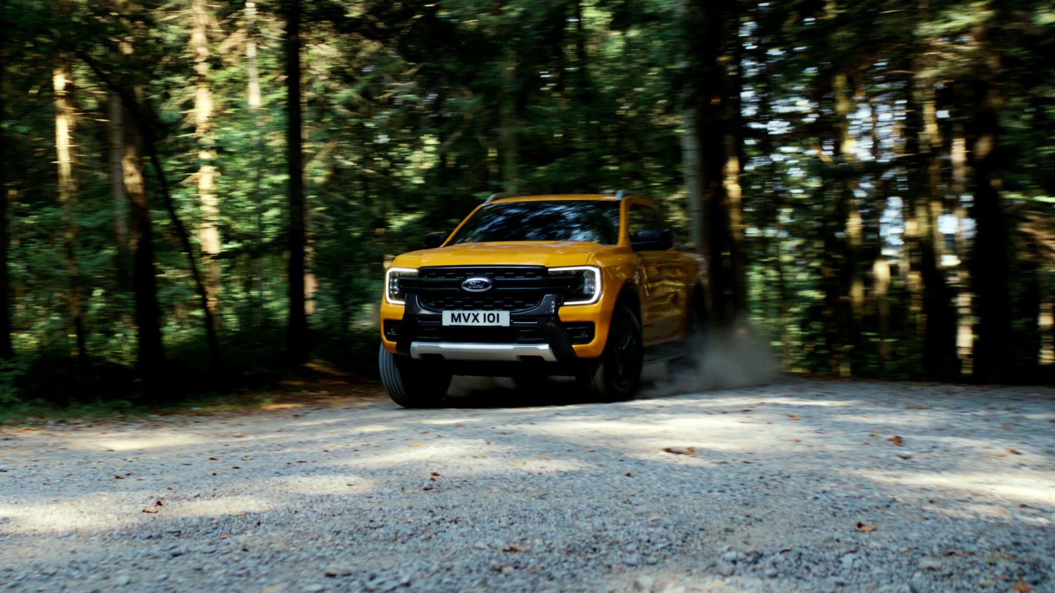 Ford Ranger in Orange. Frontansicht, fährt auf Waldweg