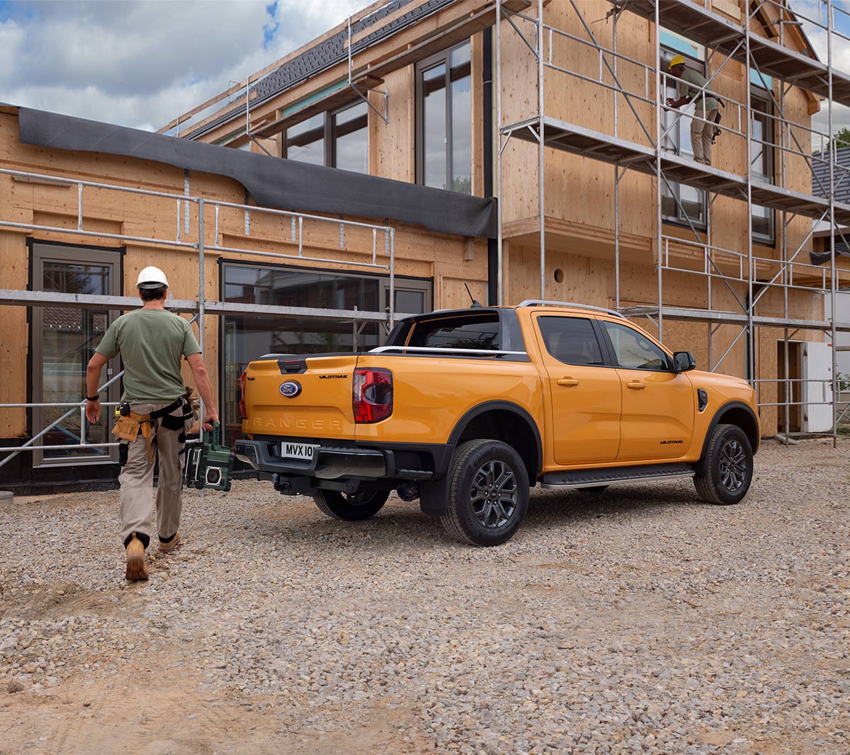 Ford Ranger in Orange. Dreiviertelansicht, parkt vor Wohnhausneubau