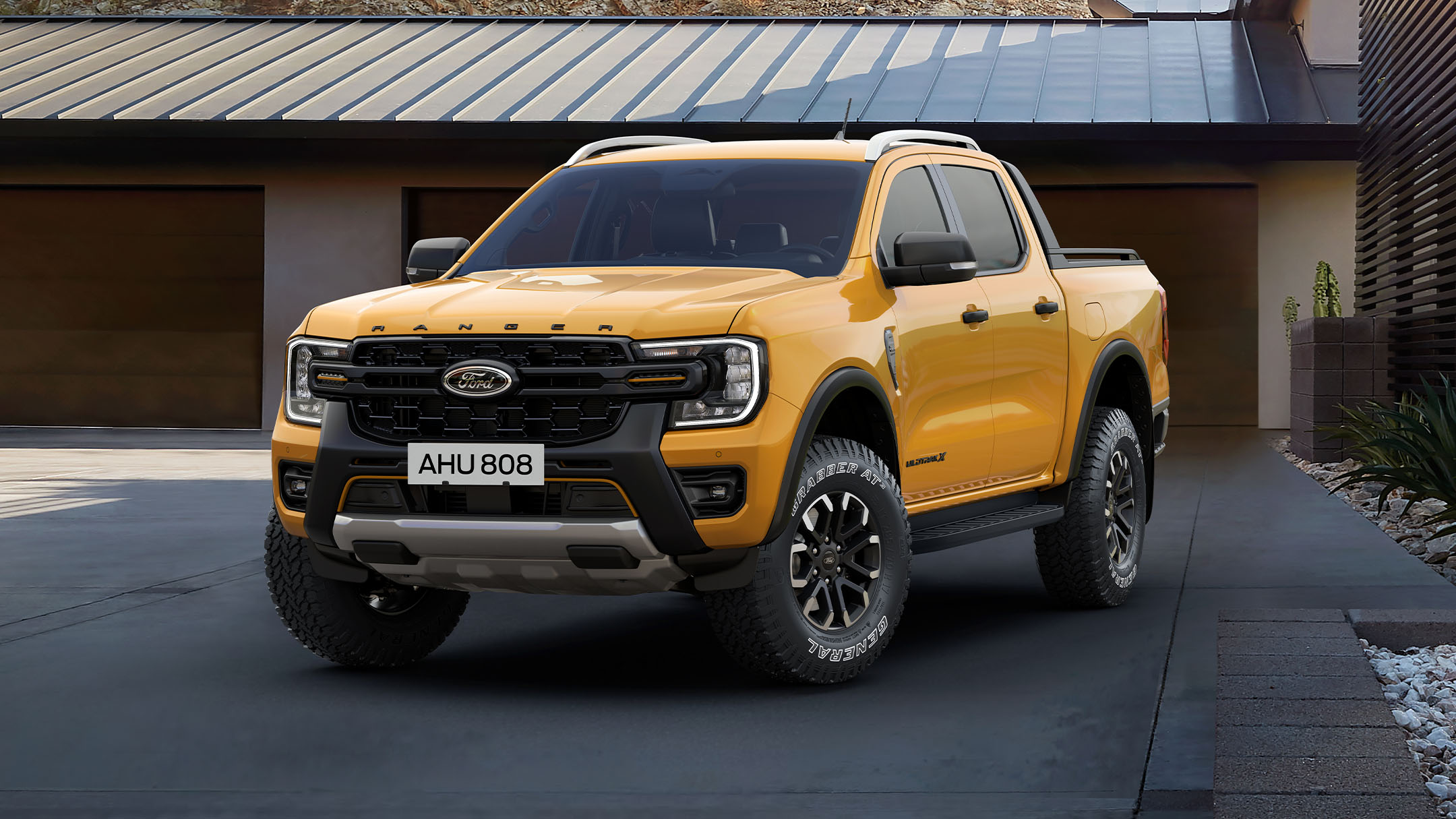 Ford Ranger Wildtrak X in Orange. Frontansicht, parkend vor einem Haus.