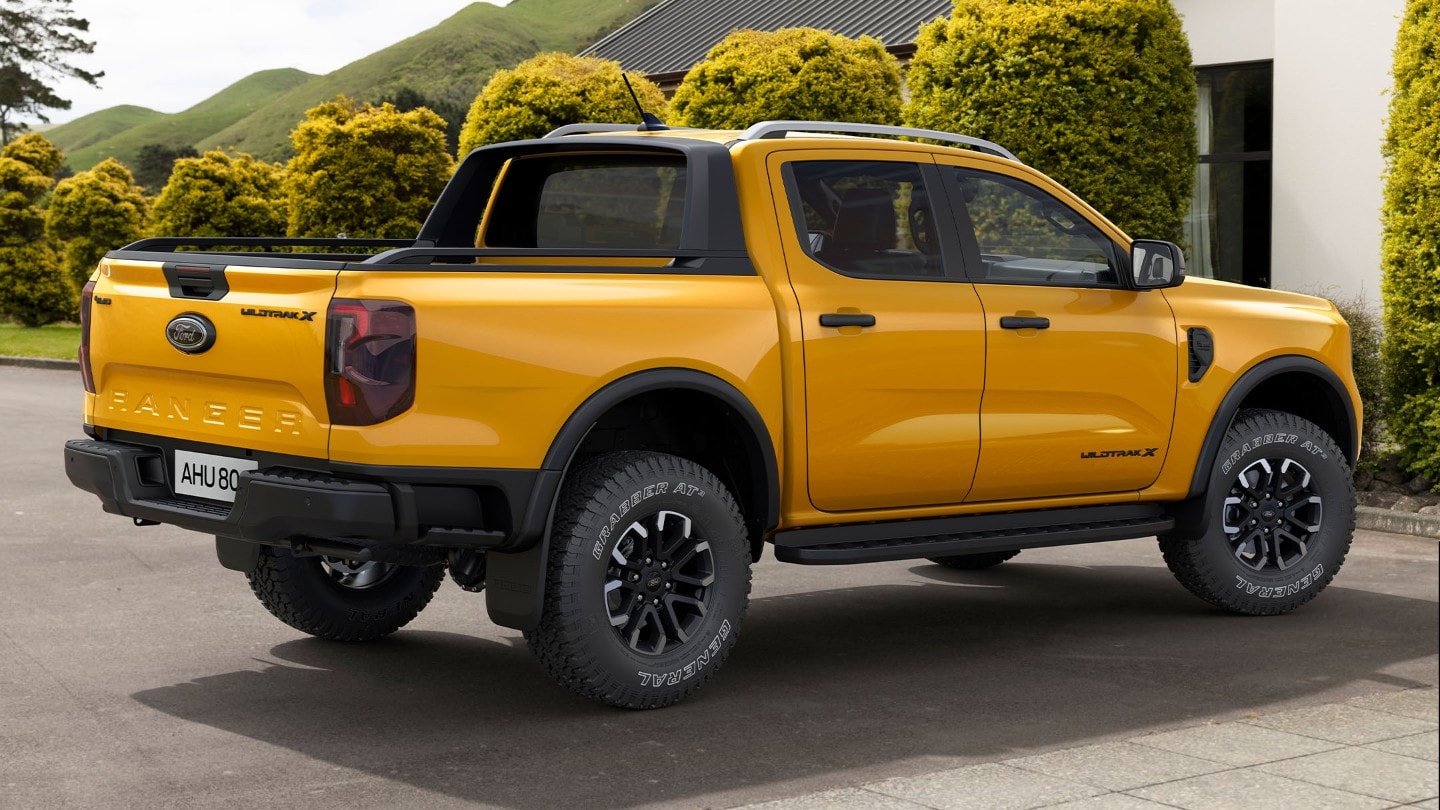 Ford Ranger Wildtrak X in Orange. Dreiviertelansicht, parkend vor einem Haus.