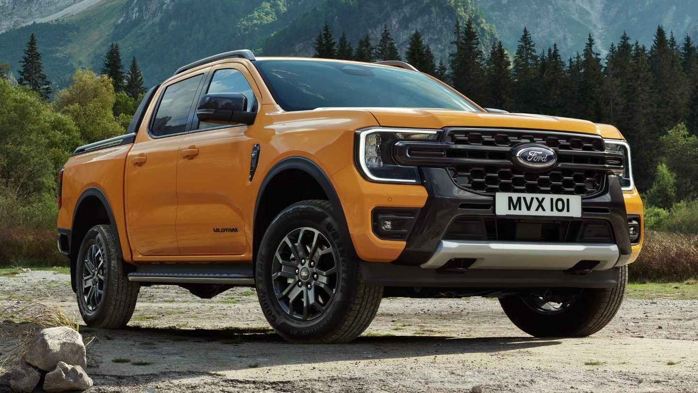 Ford Ranger in Orange. Dreiviertelansicht, parkt auf unbefestigtem Gelände im Gebirge.