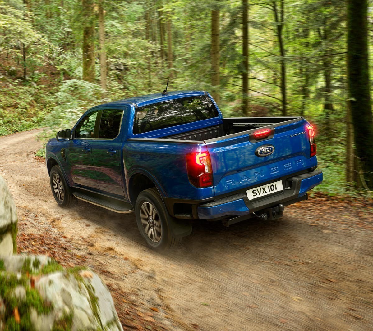 Ford Ranger in Blau. Heckansicht, fährt auf Waldweg