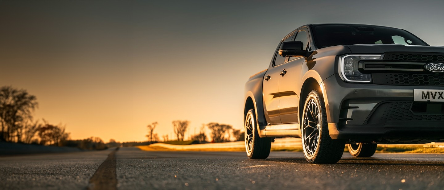 Ford Ranger MS-RT in Grau. Dreiviertelansicht, parkt auf einer Straße bei Sonnenuntergang.