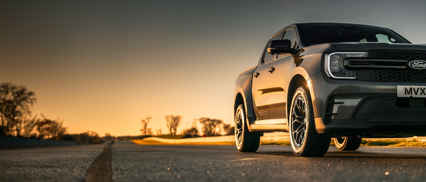 Ford Ranger MS-RT in Grau. Dreiviertelansicht, parkt auf einer Straße bei Sonnenuntergang.