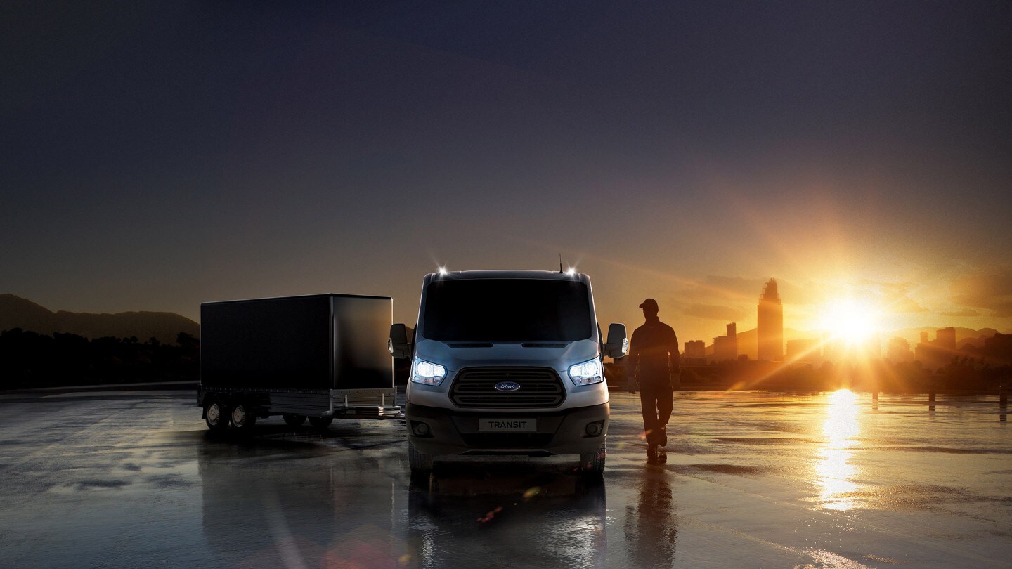 Ford Transit Pritsche in Weiß. Frontansicht, parkend auf einem nassen Platz