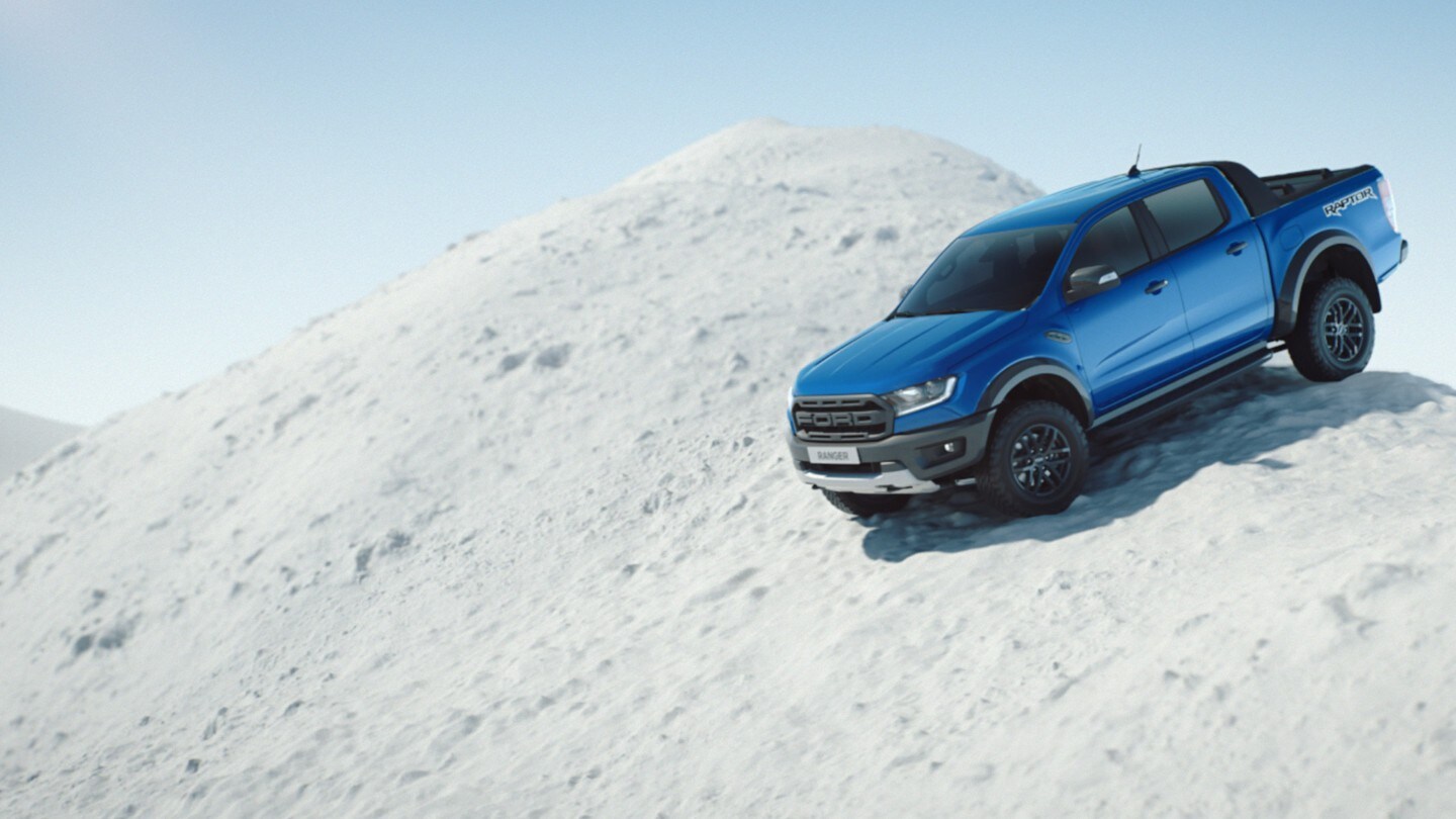 Ford Ranger in Blau. Seitenansicht, bergab fahrend auf schneebedecktem Hügel