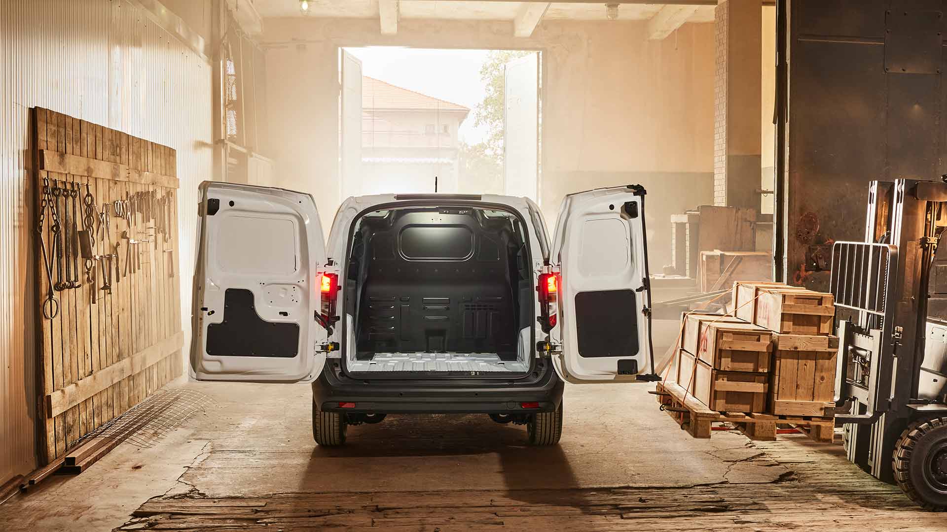 Ford Transit Courier in Weiß. Heckansicht, stehend in einer Werkstatt mit geöffneten Hecktüren.
