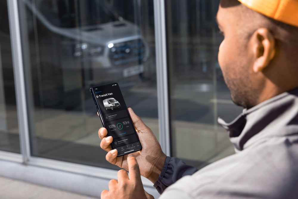Mann hält Smartphone mit geöffneter FordPass App in der Hand.