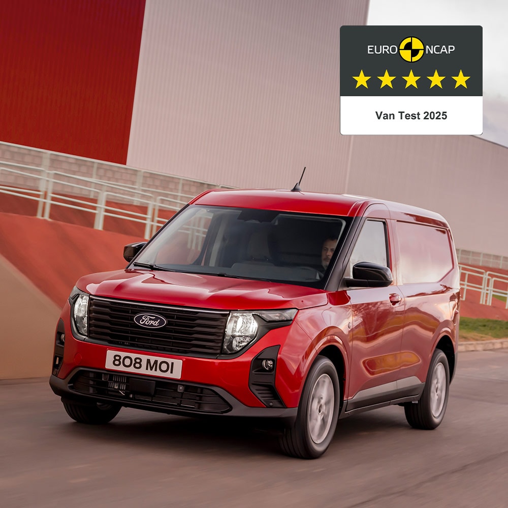 Ford Transit Courier in Rot. Dreiviertelansicht, fahrend auf einer Straße.