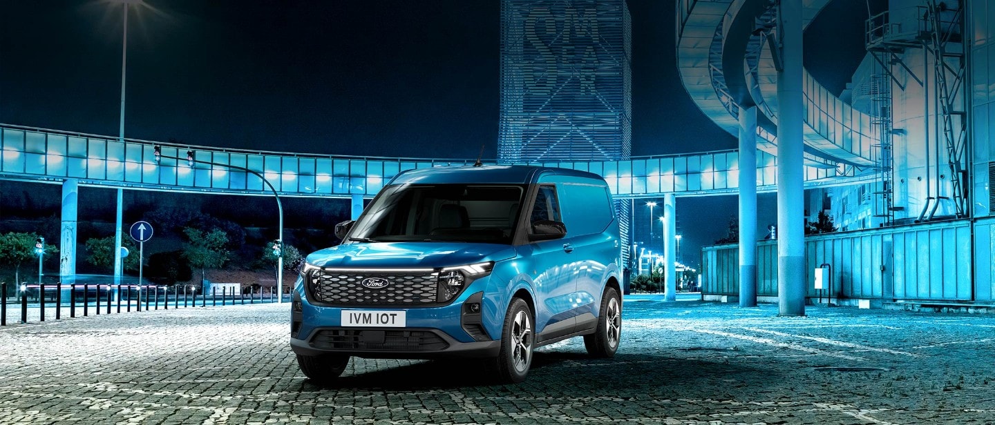 Ford Transit Courier in Blau. Dreiviertelansicht, auf einem Parkplatz bei Nacht