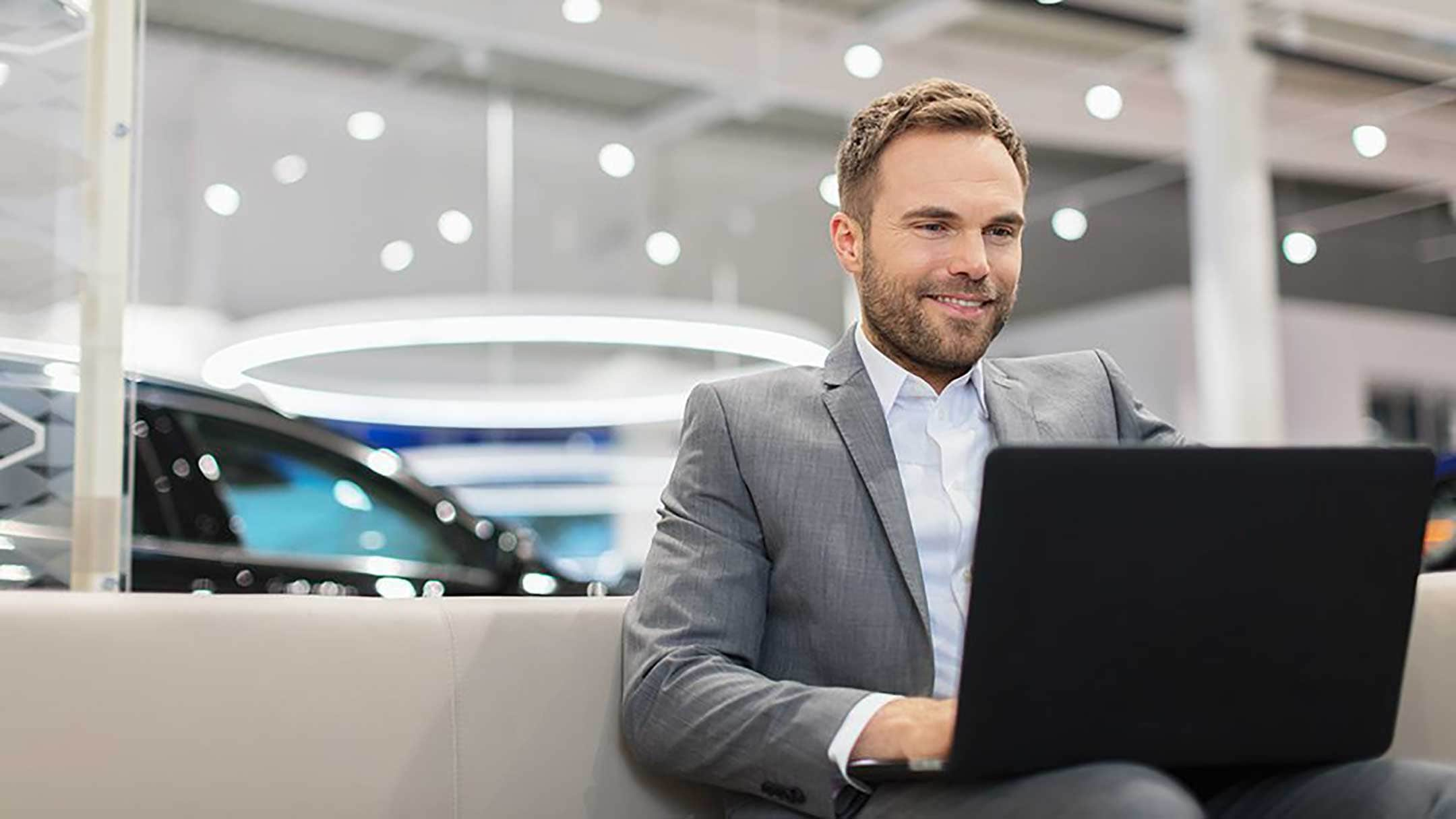 Ein Mann sitzt bei einem Ford Partner mit Laptop im Empfangsbereich