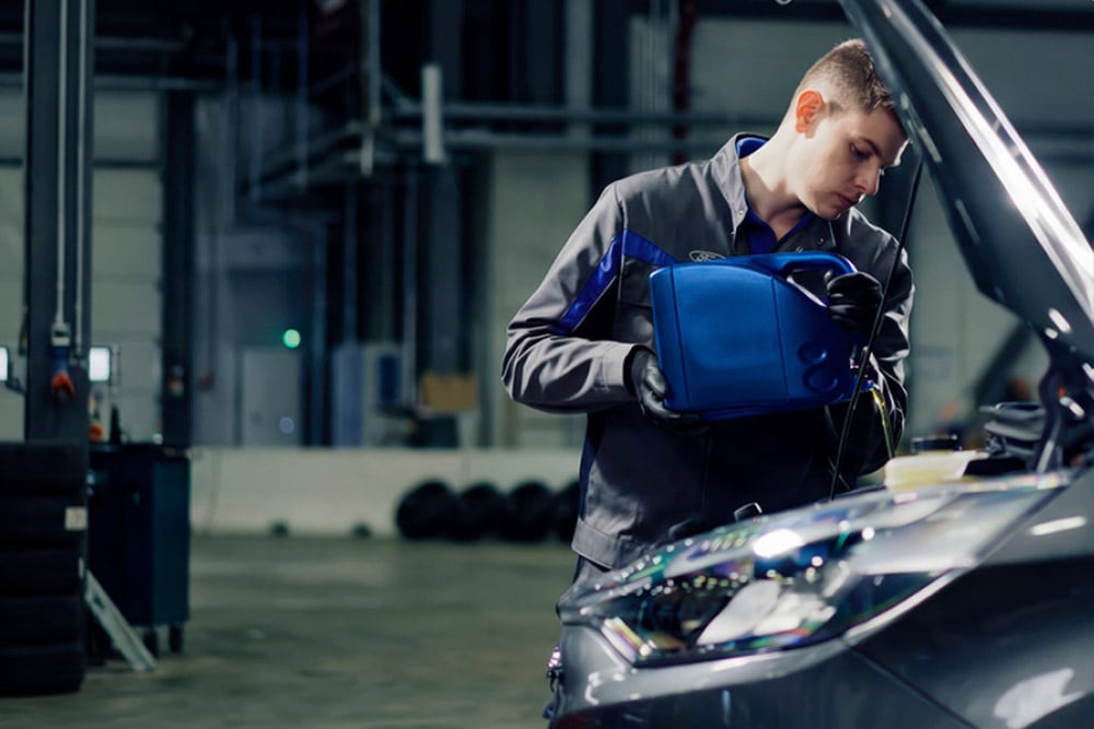 Seitenansicht eines von Ford autorisierten Technikers bei Reparaturarbeiten an einem Fahrzeug in einer Werkstatt.