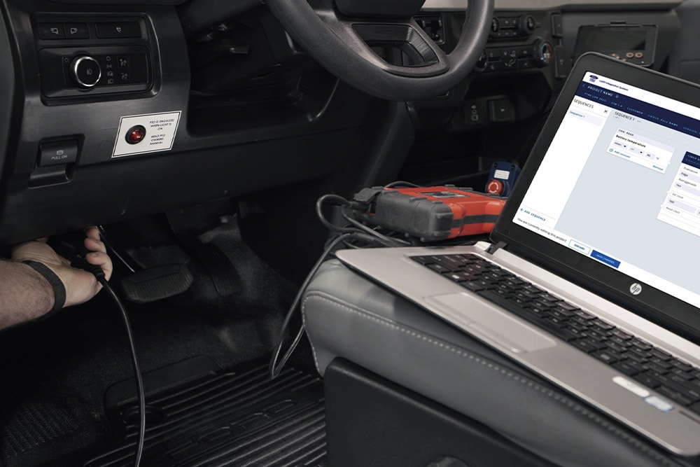 Nahaufnahme eines Laptops, der mit einem Ford Fahrzeug-Armaturenbrett verbunden ist.