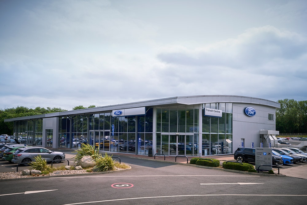 Ford Autohaus Außenansicht. Es parken unterschiedliche Ford-Fahrzeuge vor dem Gebäude.