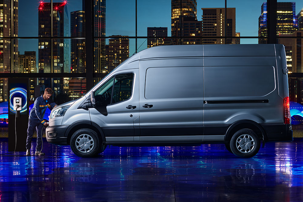  Mann lädt einen weißen Ford Transit, eine lebendige Stadtkulisse im Hintergrund.
