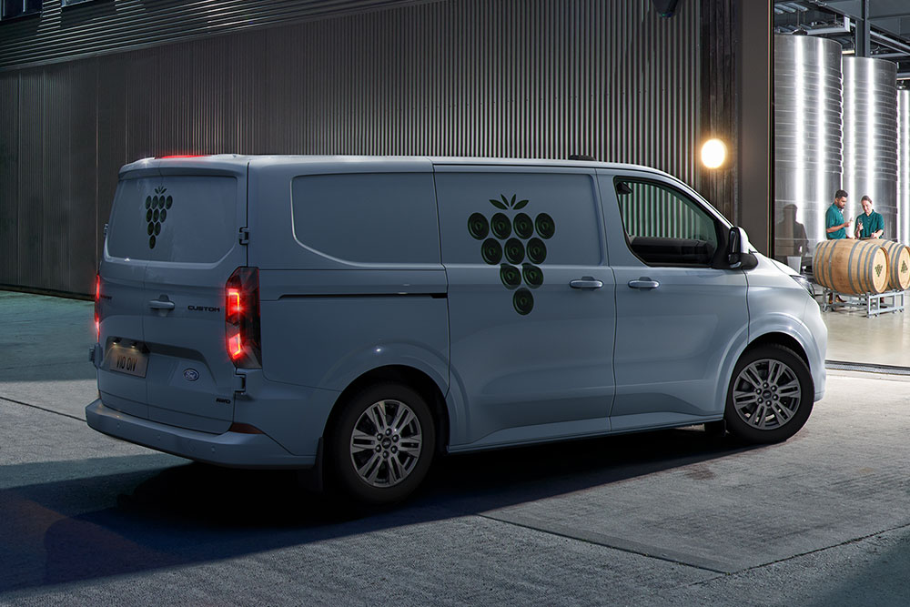 Ein weißer Ford-Transporter parkt nachts vor einem Lagerhaustor.