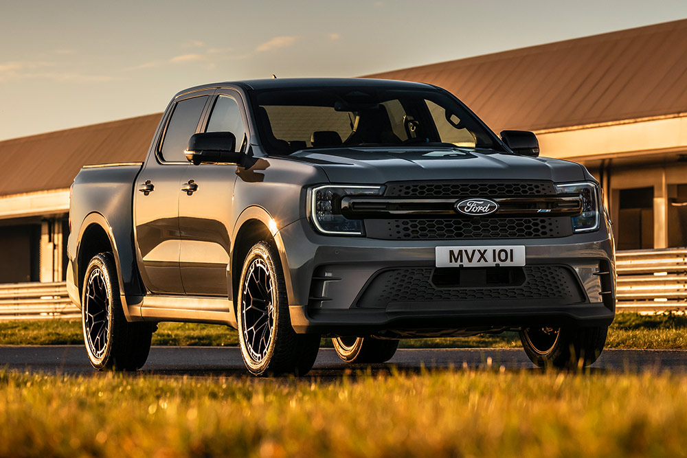 Silberner Ford Pro Ranger Plug-in Hybrid parkt vor einem Industriegebäude.
