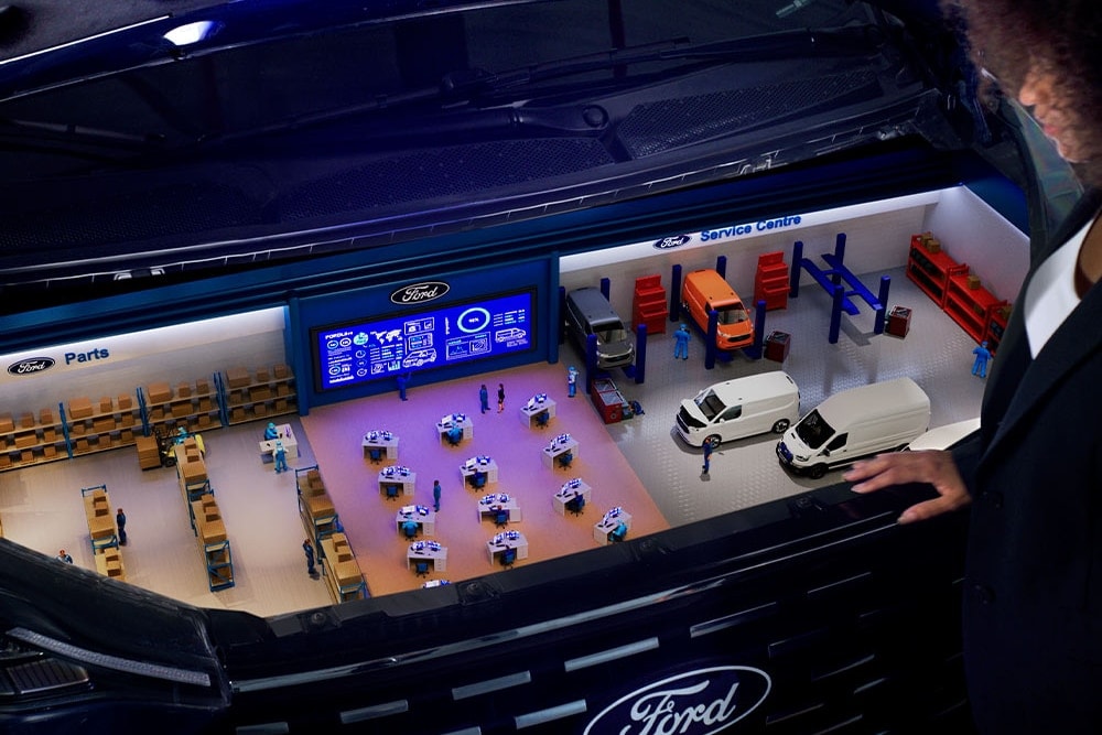  Miniaturmodell eines Ford Servicezentrums im Kofferraum eines Autos.