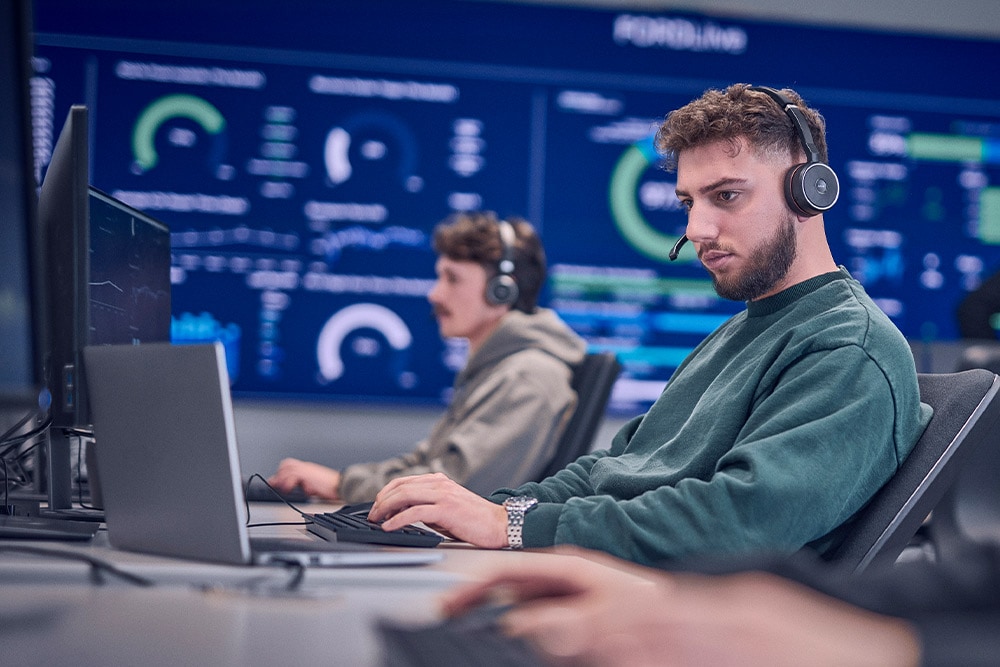  Ein Ford-Mitarbeiter trägt ein Headset und arbeitet an seinem Laptop.