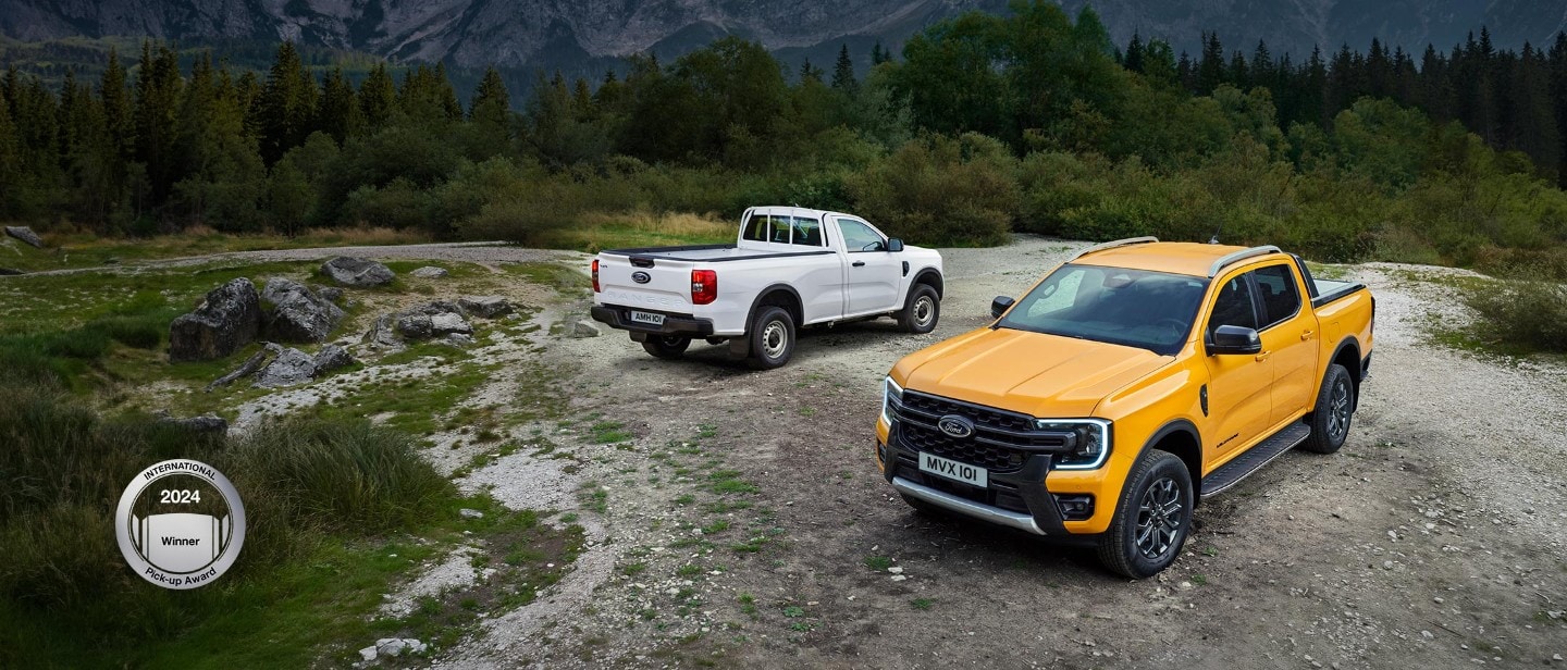 Ford Ranger in Weiß und Orange. Geparkt auf Schotterweg mit Wald und Bergen im Hintergrund