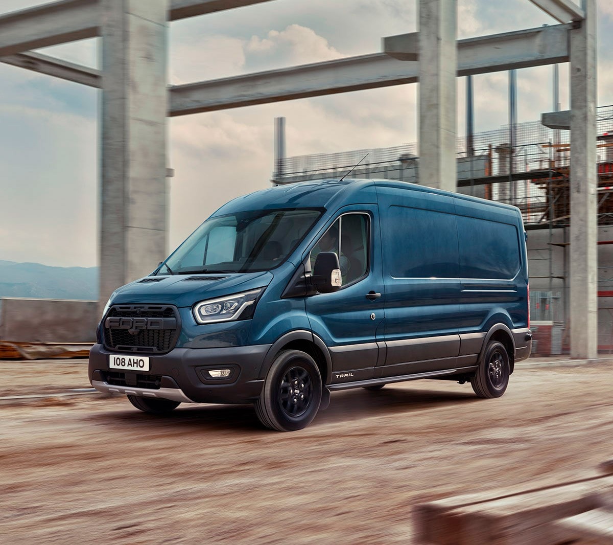 Ford Transit in Blau. Seitenansicht, fahrend über eine Baustelle