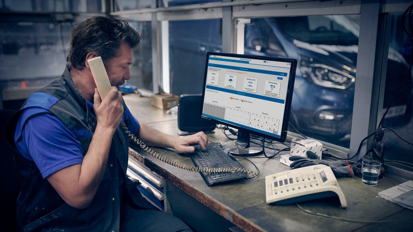 Smart Diagnostics – Mann sitz vor Computer in einer Werkstatt und telefoniert